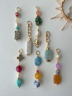 several different types of beaded charms on a white surface with a sun in the background