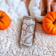 an orange and white pumpkin sitting on top of a blanket next to a glass cup