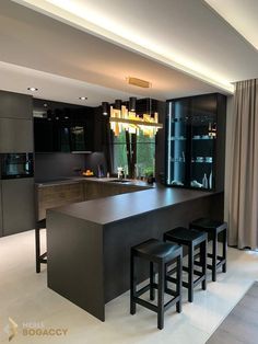 a modern kitchen with an island and bar stools in the center, surrounded by black cabinetry