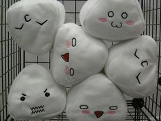 a pile of white pillows with faces drawn on them in a wire basket for display