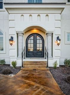 a large white house with black doors and steps leading up to the front entry door