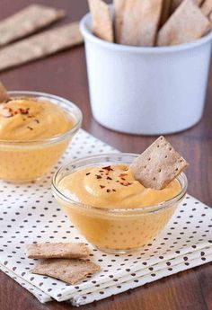 two small bowls filled with hummus and crackers