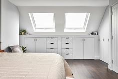 a white bedroom with two skylights above the bed and drawers on either side of the bed