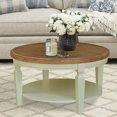 a coffee table with flowers on top in front of a couch and rugs around it