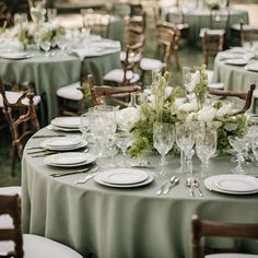 the table is set with white and green flowers in vases, silverware, and wine glasses