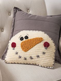 a crocheted snowman pillow sitting on top of a couch next to a chair