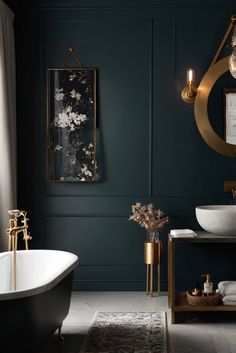 a bathroom with dark green walls and gold fixtures on the sink, bathtub, and rug