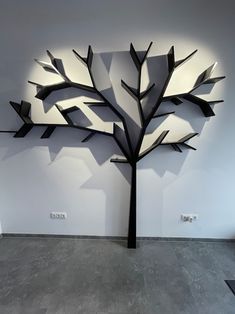 a metal tree sculpture sitting on top of a cement floor next to a white wall