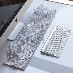 a computer keyboard sitting on top of a desk next to a model of a city