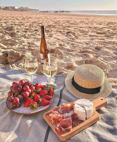 strawberries and cheese on a beach with a bottle of wine