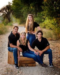 three people are posing for a photo on a wooden crate in the middle of a dirt road