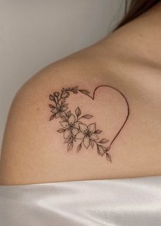 a woman's shoulder with flowers and a heart tattoo on her left side breast