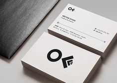 two business cards sitting on top of each other next to a black piece of paper