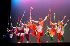 a group of people standing on top of a stage holding up sticks and poles in the air