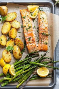 salmon, potatoes and asparagus on a baking sheet with lemon wedges for garnish