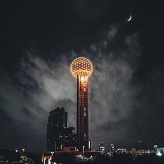 a tall tower with a light on it's side in the middle of a city at night