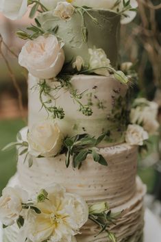 a multi layer wedding cake with flowers on the top and bottom tier is decorated with greenery