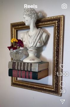 a white busturine sitting on top of a pile of books next to a vase with flowers