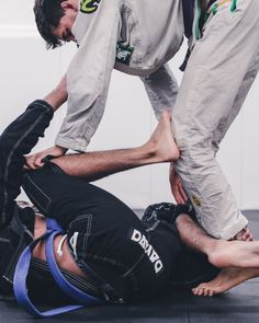 two men in black and white uniforms are doing an armbar on another man's back