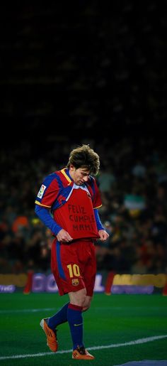 a soccer player in red and blue is running on the field with his head down