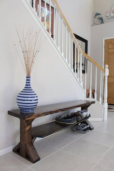 a blue and white vase sitting on top of a wooden bench next to a stair case