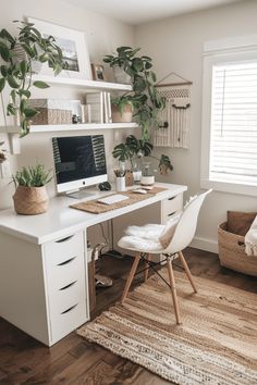 a white desk with a computer on top of it next to a chair and potted plant