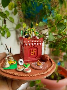 a miniature house on a tray with plants in the background