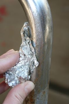 a person holding something in their hand near a piece of tin foil on a metal object