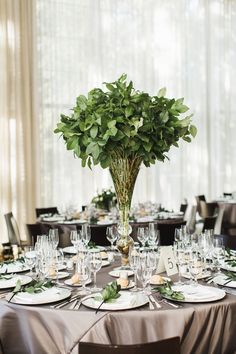 there is a table set with place settings and flowers in vases on the tables