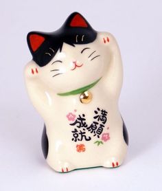 a white and black cat figurine with chinese writing on it's chest