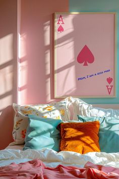 a bed topped with lots of pillows next to a pink wall