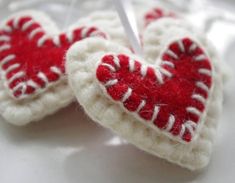 two crocheted heart ornaments hanging on a white tablecloth with red and white trim