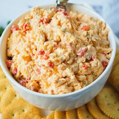 a white bowl filled with chicken salad surrounded by crackers