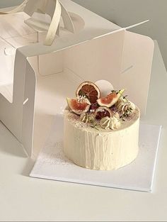 a white cake with fruit on top in a box