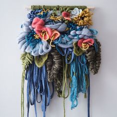 a wall hanging made out of yarn with flowers on it