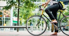 a woman is riding her bike down the street in front of some trees and buildings