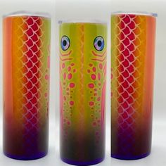 three different colored cups with fish designs on the sides and one has eyes painted on it