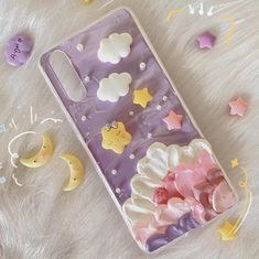 a phone case with stars, clouds and moon shapes on the back is laying on a fur surface