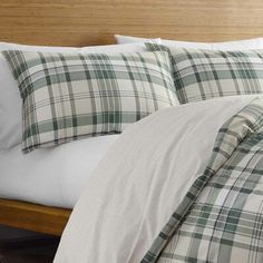 a bed with white and green plaid comforter on it's side, next to a wooden headboard