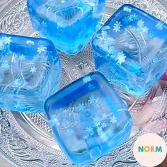 four blue ice cubes sitting on top of a glass plate covered in snowflakes