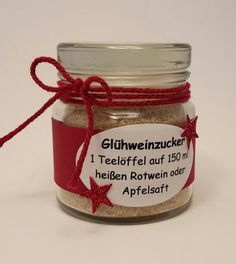 a glass jar filled with red and white stuff next to a tag on the lid