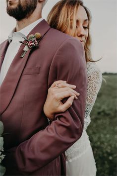 a man and woman standing next to each other in front of a field with grass