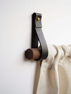 a coat rack is mounted on the wall by a curtain rod with a wooden handle