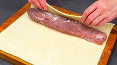 a person cutting meat on top of a piece of paper with a wooden spatula