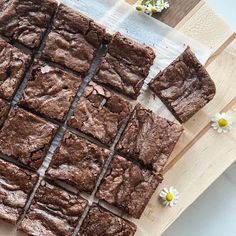 chocolate brownies cut into squares on a cutting board with daisies in the background