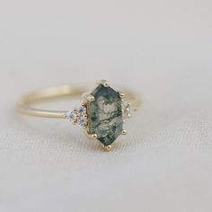 a close up of a ring with a green stone and diamonds on the bottom side