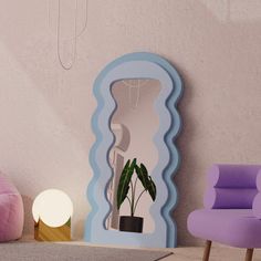 a mirror sitting on top of a wooden floor next to a purple chair and potted plant