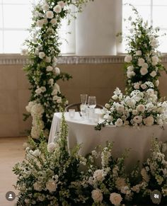 the table is set with white flowers and greenery for an elegant wedding reception or special event