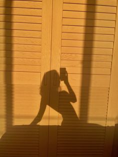 the shadow of a person holding a cell phone up to their ear and standing in front of a wooden door