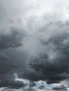 an airplane is flying in the sky with dark clouds above it and another plane on the ground below